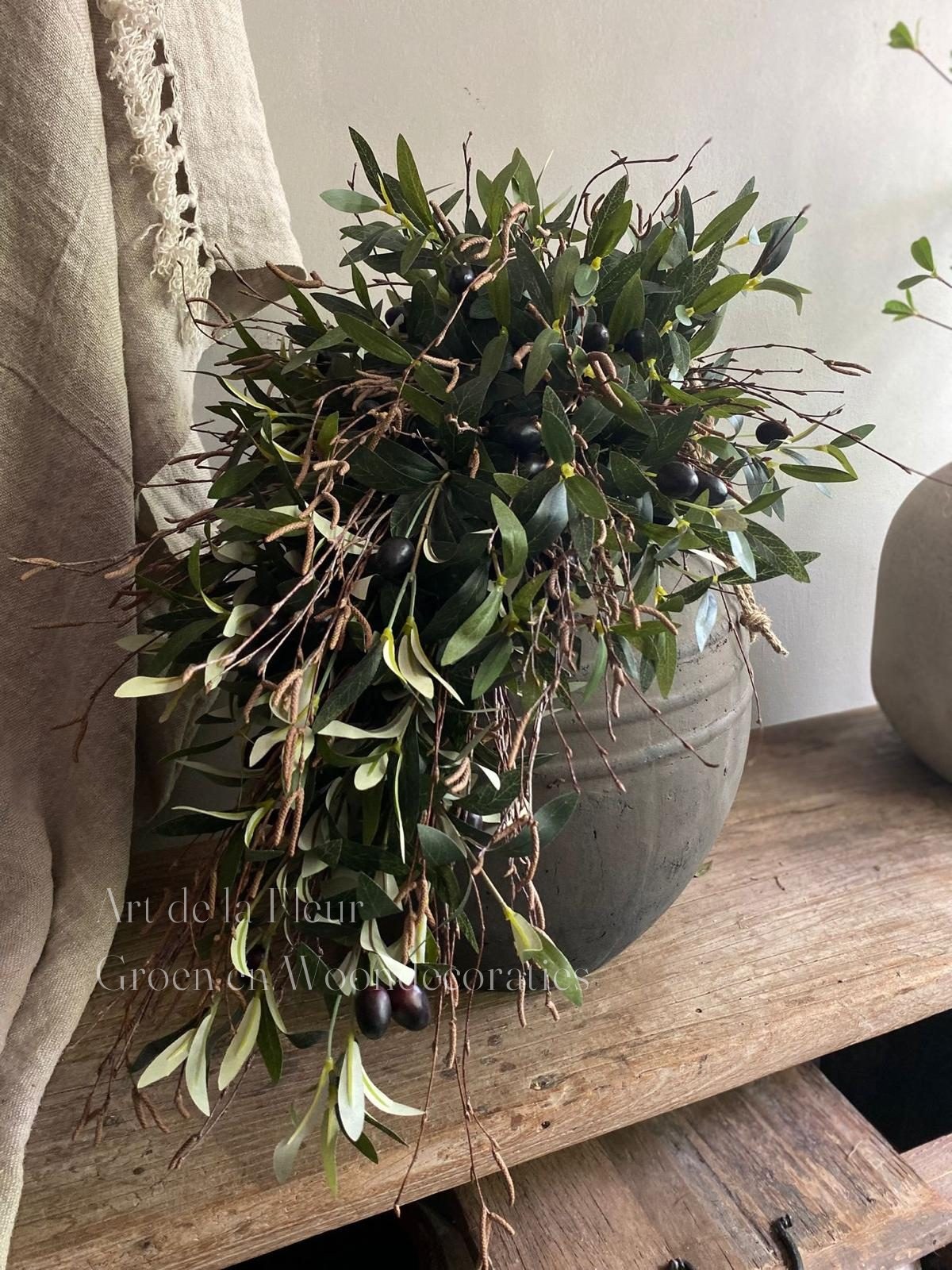 Toef van olijf en eucalyptus over een oude kruik op een houten tafel