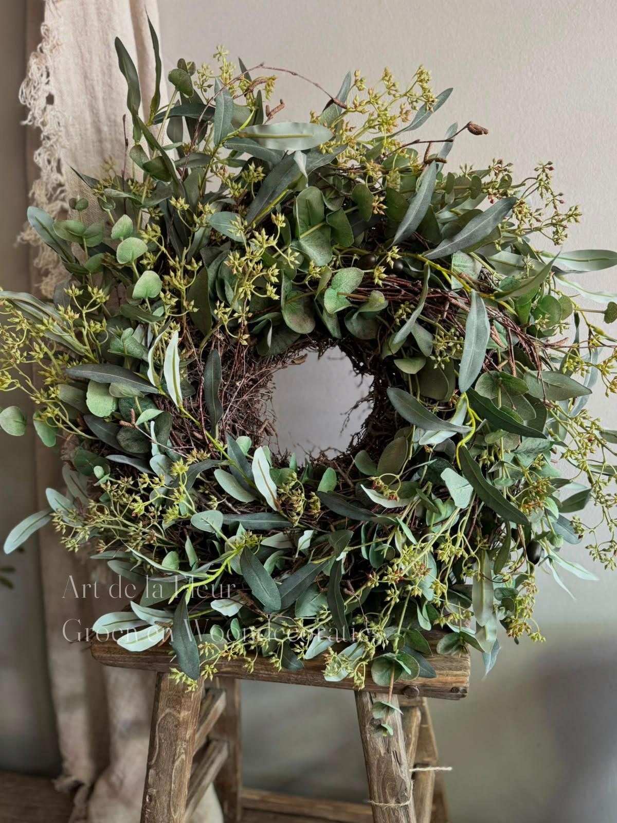 Krans van eucalyptus en olijf op een oud houten krukje
