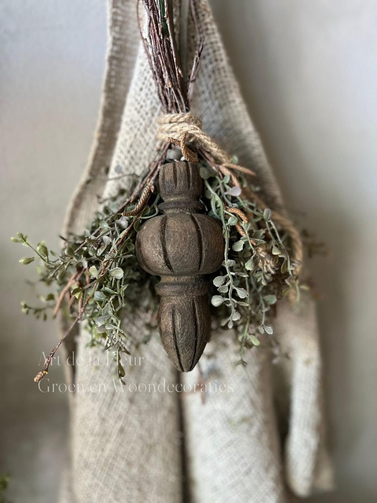 Toefje van eucalyptus rond een houten ornament tegen een kalkwand