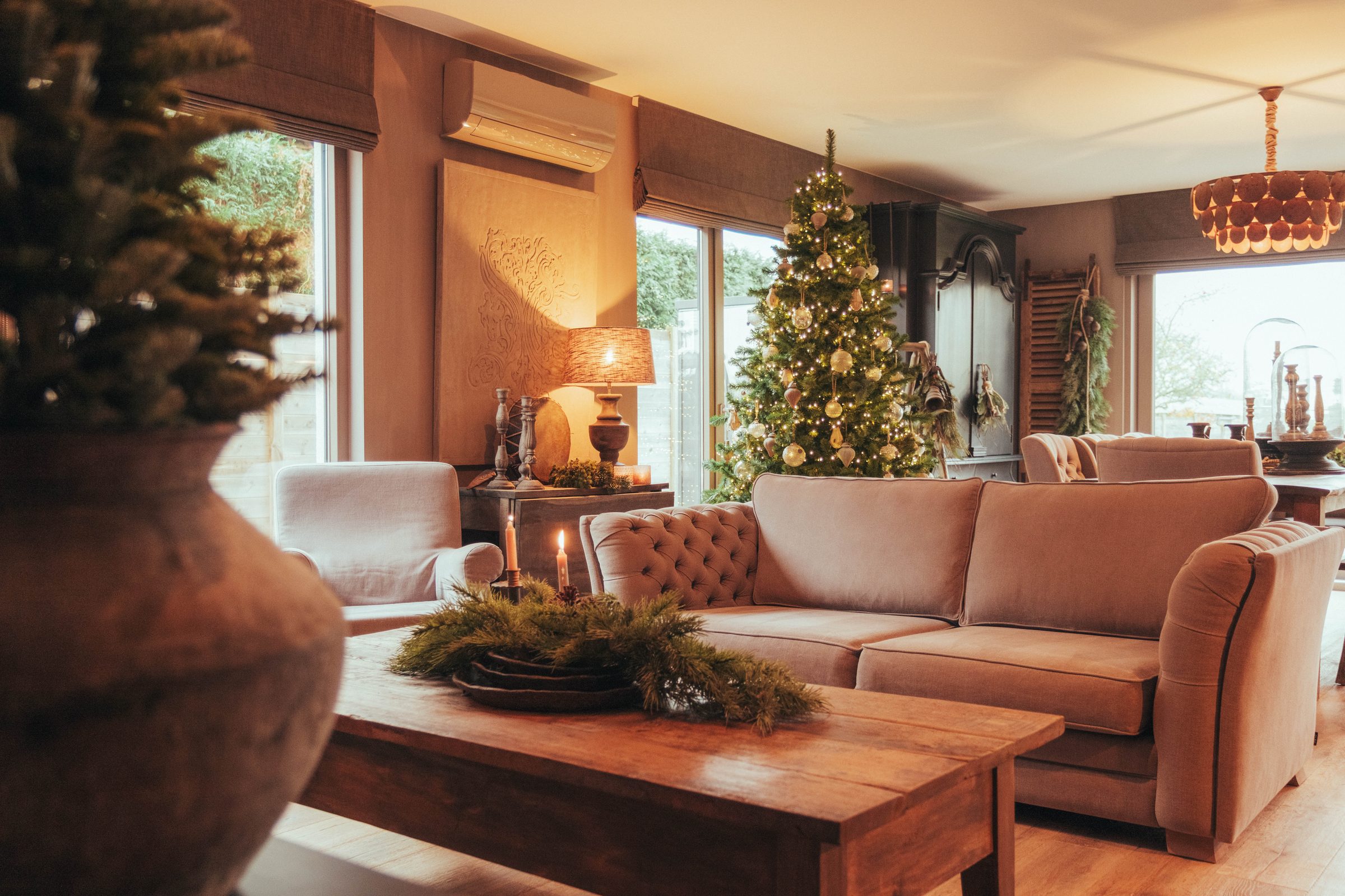 Warme woonkamer in kerstsfeer met zetels, kaarsen en kerstboom — Nina kersteditie 2025