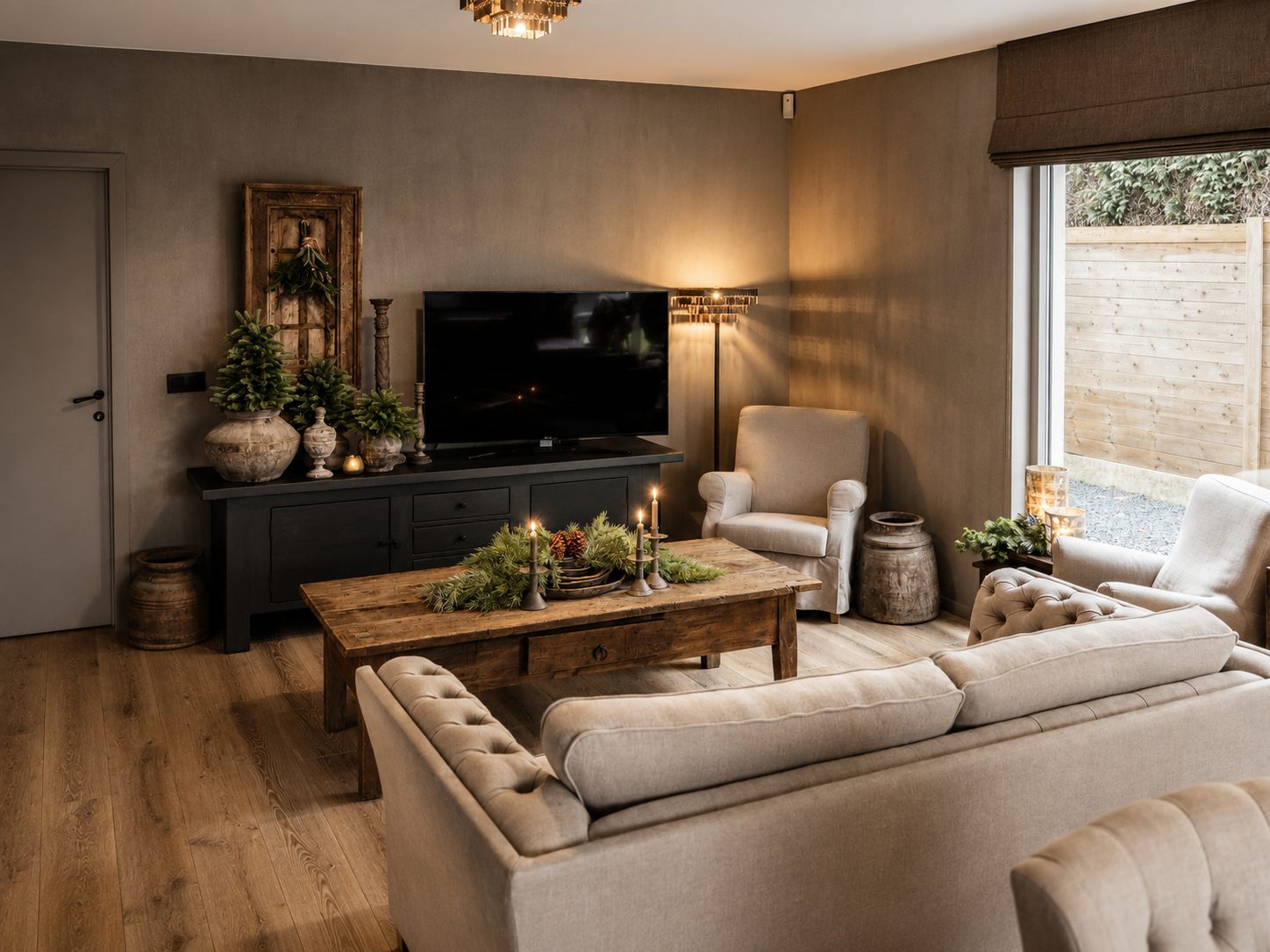 De leefruimte in kerstsfeer: zachte sofa's rond de oude salontafel met kaarslicht