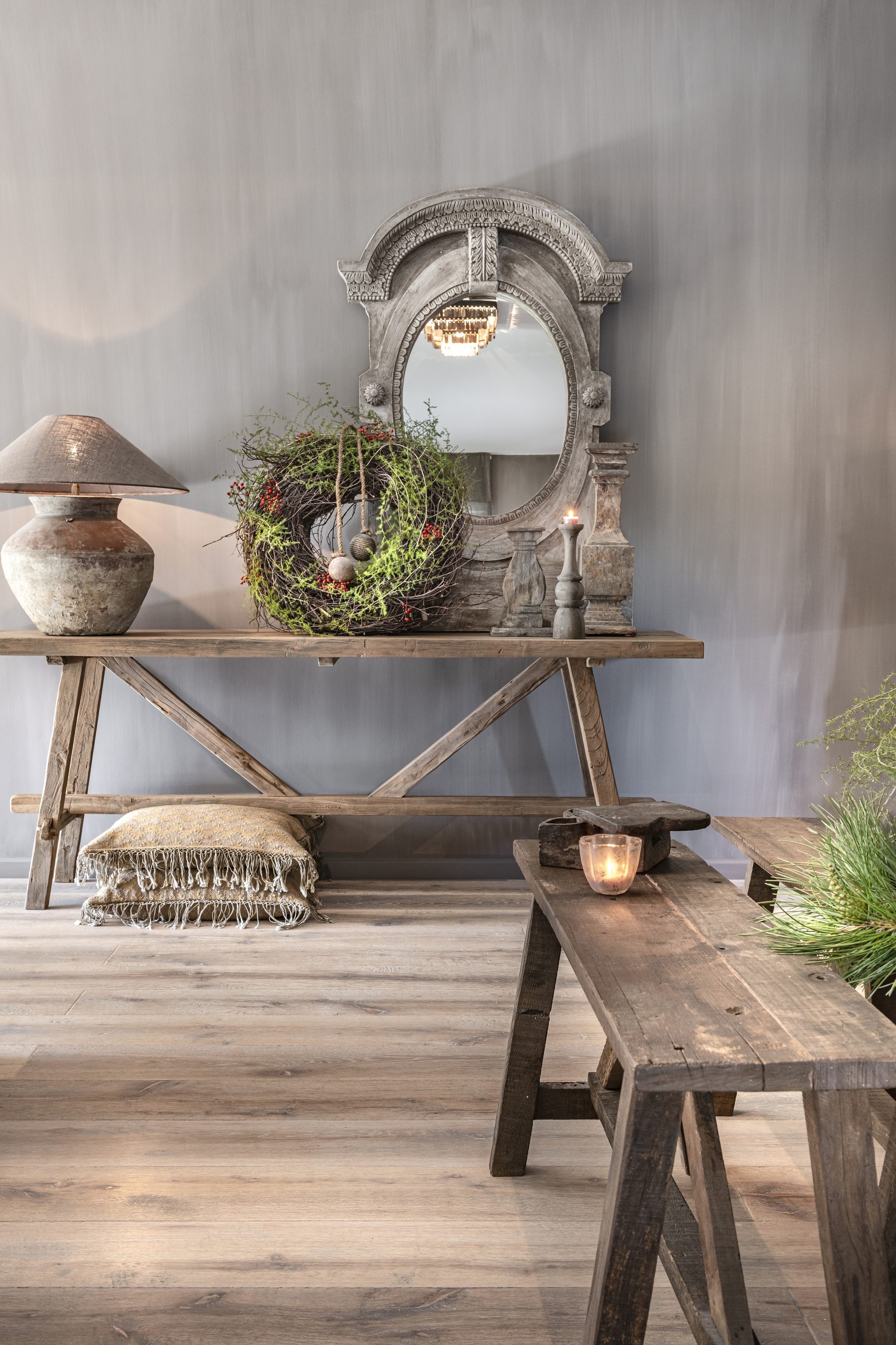 Heldere hoek met houten wandtafel, antieke spiegel, groene krans en kruikenlamp