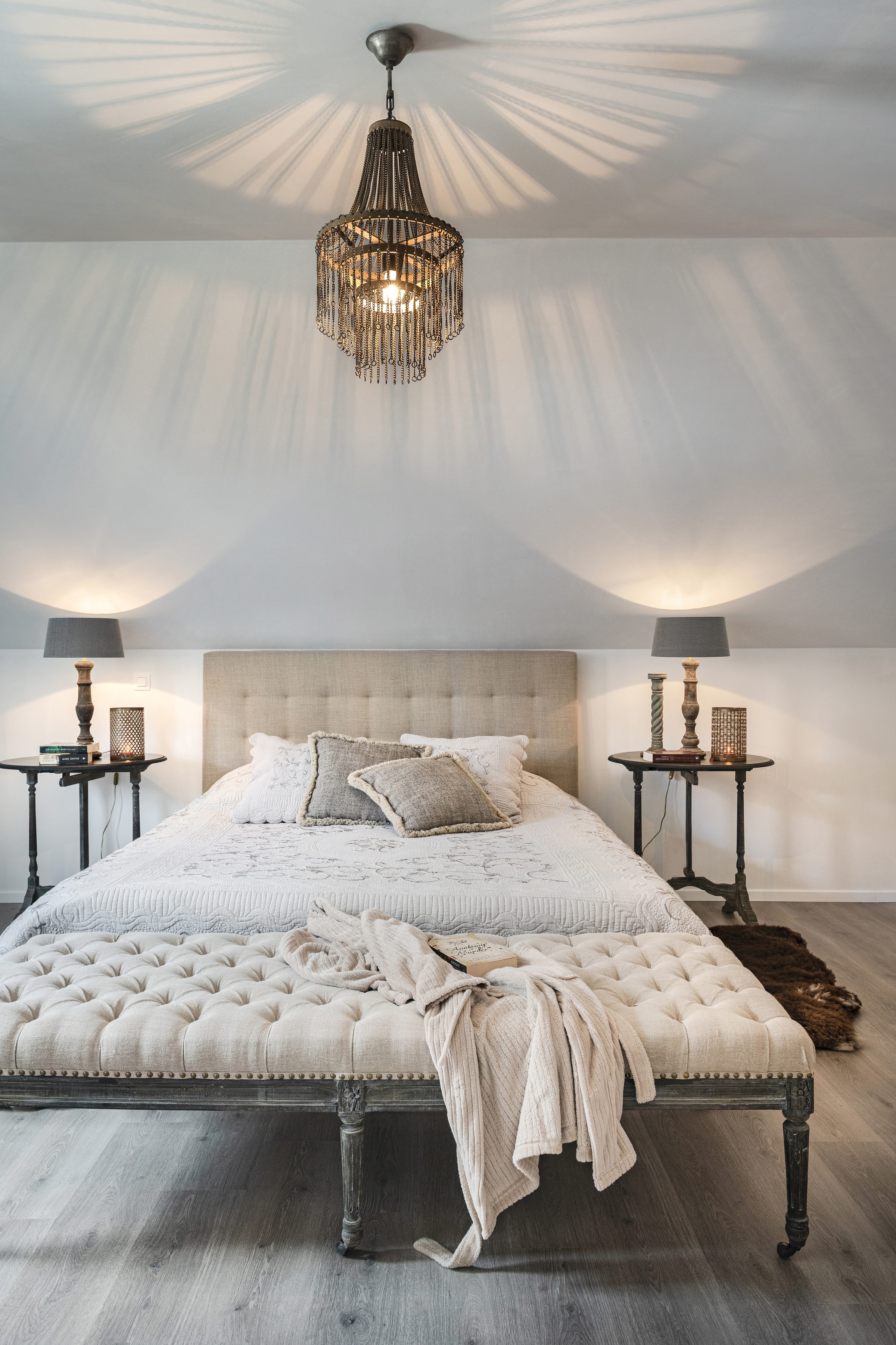 Lichte slaapkamer met gestoffeerd bed en linnen hocker